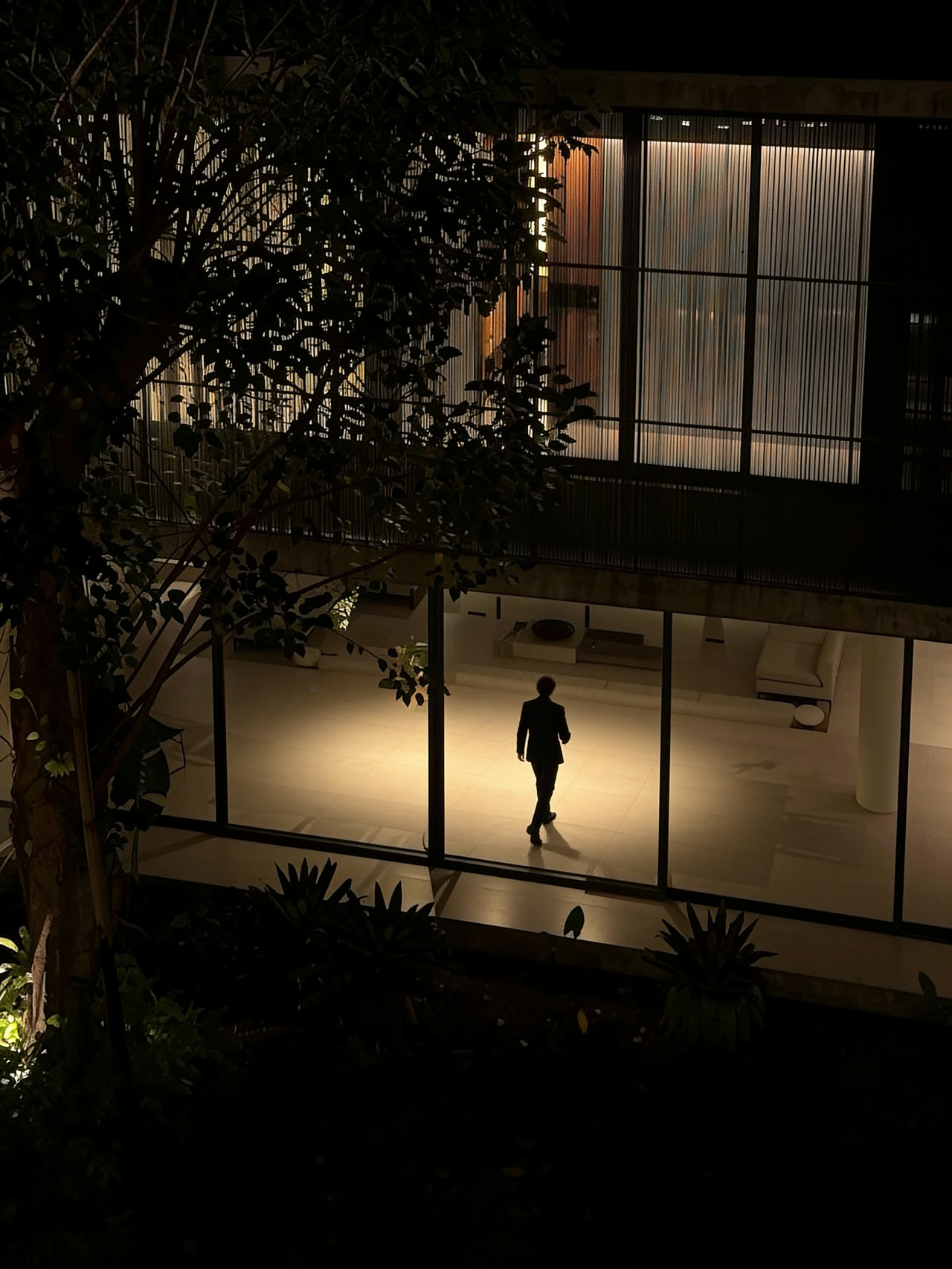 Alex Habeeb crossing a lit glass-walled interior at night